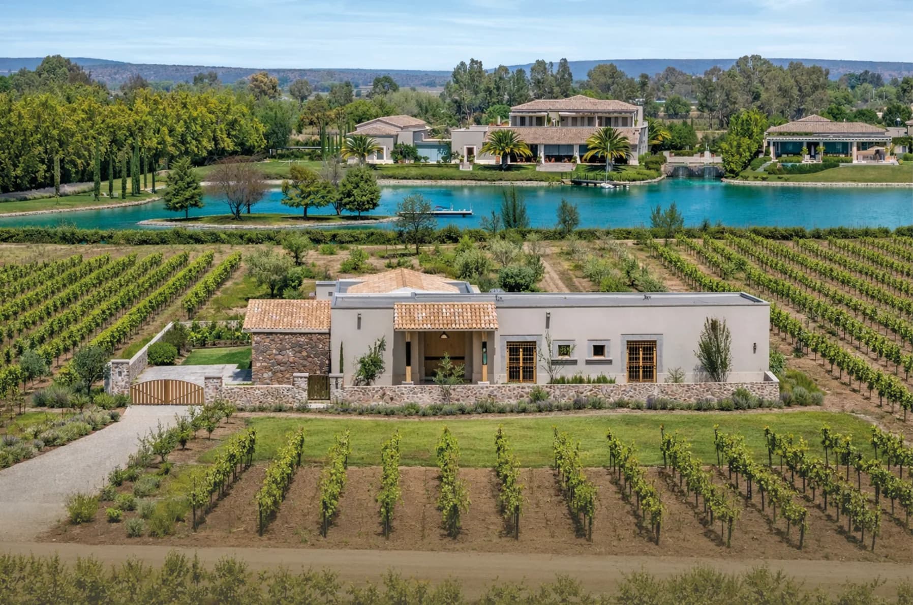 Aerial view of Casa Roble, a single-level home set among vineyard rows beside a reservoir in San Miguel de Allende