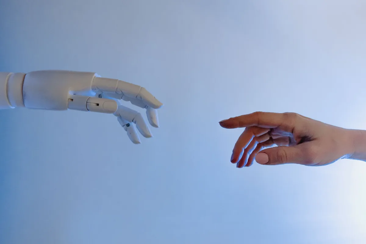 A robotic hand and a human hand reaching toward one another
