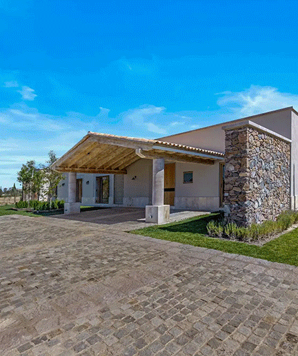 The stone-and-stucco entrance of Casa Roble beneath a tiled portico, approached by a cobblestone drive